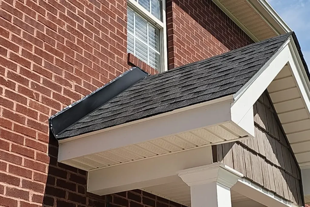 Detailed view of newly installed roof flashing along brick wall and shingle roof, illustrating correct prevention of roof flashing damage by Skyline Contracting