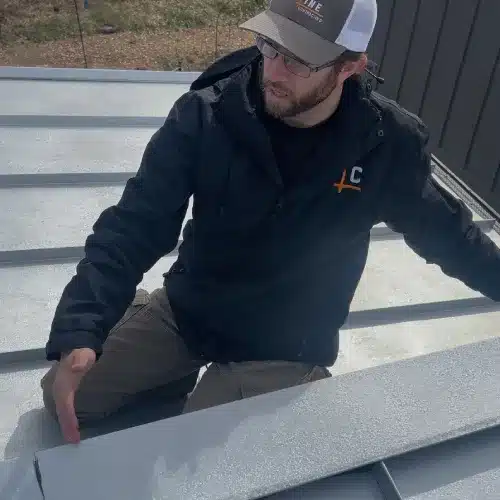 Professional roofing contractor inspecting seams and panels during metal roof repair by Skyline Contracting in GA