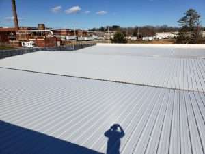 a newly retrofitted metal roofing system with the shadow of the contractor taking a photo