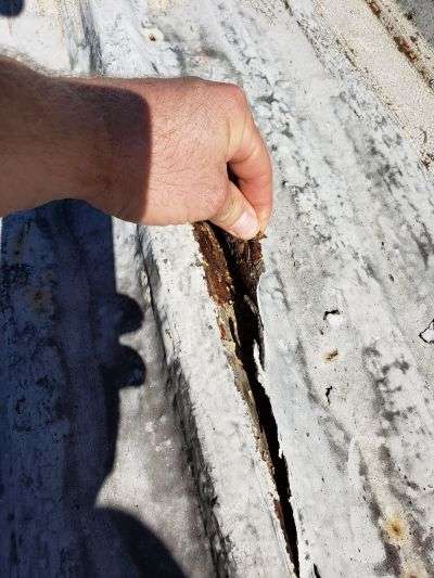 a roofing contractor examines a deteriorating metal roofing system