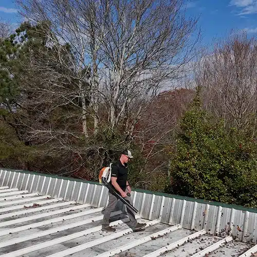 Technician cleaning and inspecting a metal roof as part of roof inspections in Gainesville by Skyline Contracting