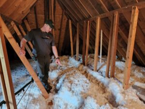 a roofer inspects an attic for signs of poor ventilation