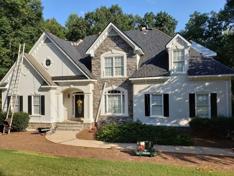 Front view of a residential roof repair project with ladder resting on roof