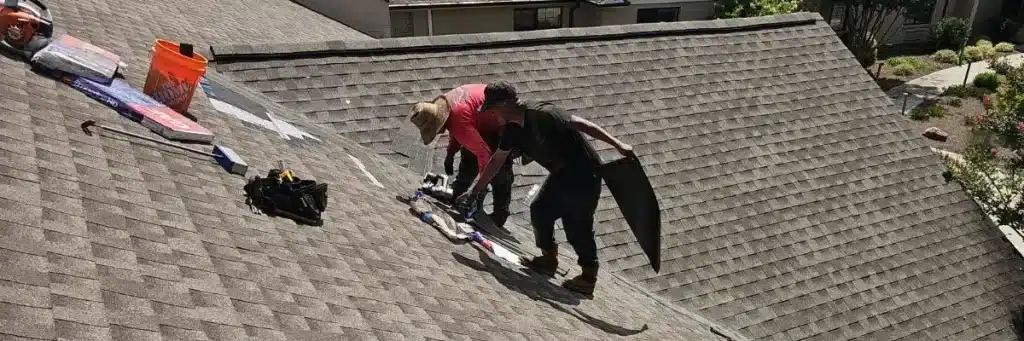 Two contractors working on residential shingle roof leak repair with materials and tools, illustrating roof leak repair cost by Skyline Contracting
