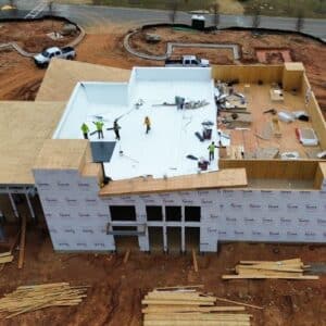 Aerial view of a commercial roofing services in progress, showing the roof partially covered with white material in Gainesville, GA