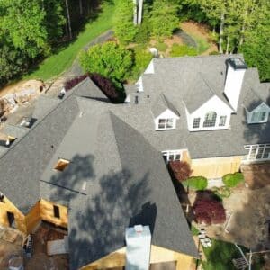 Aerial view of a large house with a newly installed gray shingle roof by certified roofing specialists in Gainesville, GA