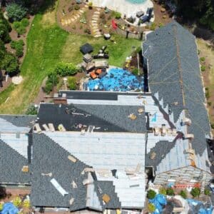 Aerial view of a large house with an on-going roof installation by certified roofing specialists in Gainesville, GA