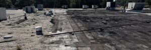 A slightly angled aerial view of a flat, commercial rooftop with various HVAC units and pipes, showing signs of wear and needing commercial roof repair by Skyline Contracting in Gainesville, GA