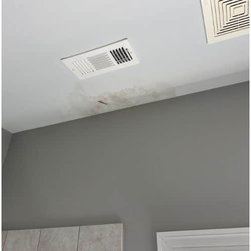 Two ceiling air vents, one rectangular with visible staining around it