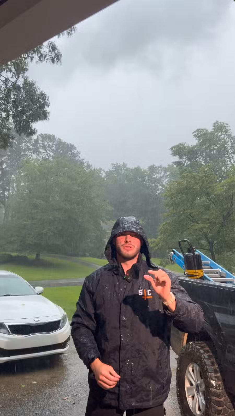 Skyline Contracting team member Max Forbes standing in heavy rain in Gainesville, GA, emphasizing the importance of emergency roof leak repair services.