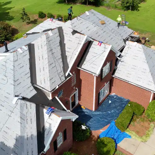 Roofing crew installing underlayment on large home roof to extend what is the lifespan of a roof by Skyline Contracting