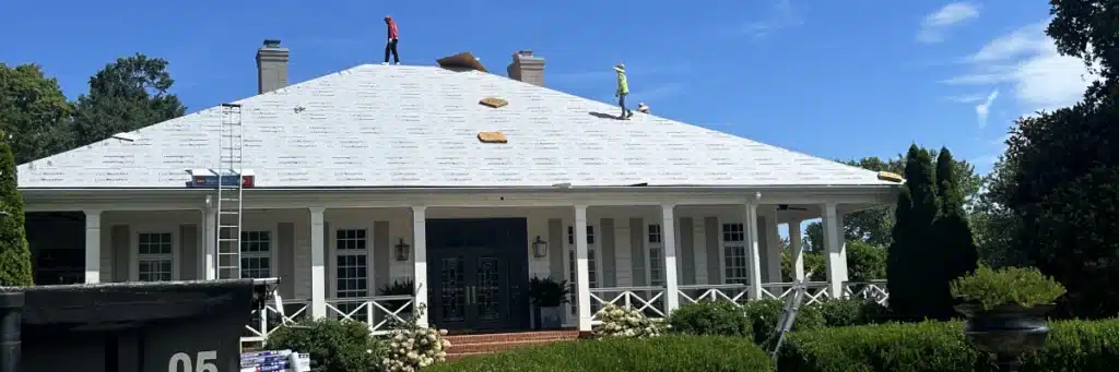 Professional roofers installing underlayment on a large residential roof, demonstrating essential components included in a roofing estimate by Skyline Contracting