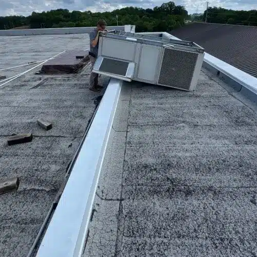 echnician performing commercial roof maintenance and inspecting rooftop HVAC unit for optimal performance by Skyline Contracting