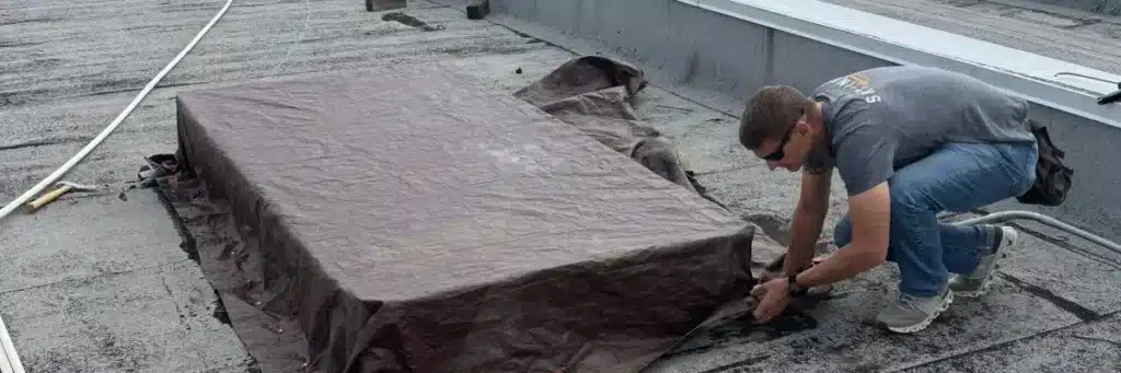 Commercial roof maintenance in progress with technician repairing flat roof by Skyline Contracting