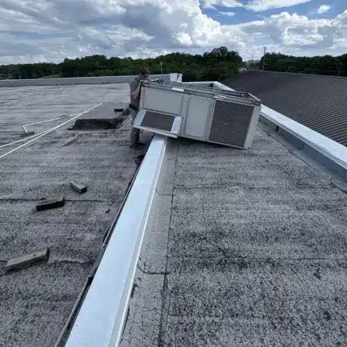 Commercial roofing technician performing maintenance on a flat roof HVAC unit to maximize roof lifespan and ROI – Skyline Contracting.