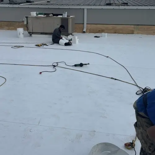 Contractors performing professional commercial flat roof repair using white roofing membrane material by Skyline Contracting