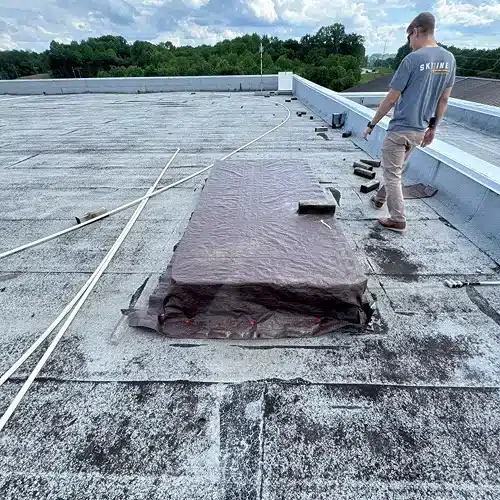 Roofing professional inspecting worn membrane and seams on a commercial flat roof by Skyline Contracting in Gainesville, GA