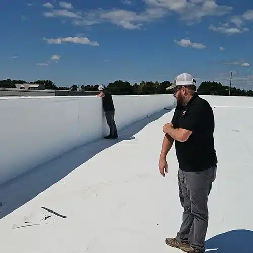 Two commercial roofing technicians inspecting roof seams and flashing by Skyline Contracting in Gainesville, GA