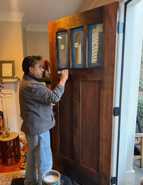 Expert applying stain during professional entry door installation for window & door installation project by Window & Door Installation Gainesville | Skyline Contracting