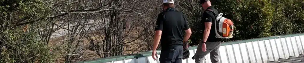 Technicians inspecting a metal roof edge and drainage to spot roof inspection problem areas by Skyline Contracting in Gainesville