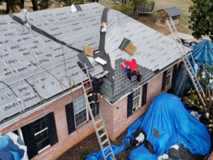 Roofing contractors installing shingles on a residential home during a roof replacement
