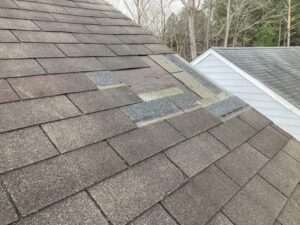 A wide view of an asphalt shingle roof with a few visible repair areas, representing roof warranty and repair considerations for homeowners.