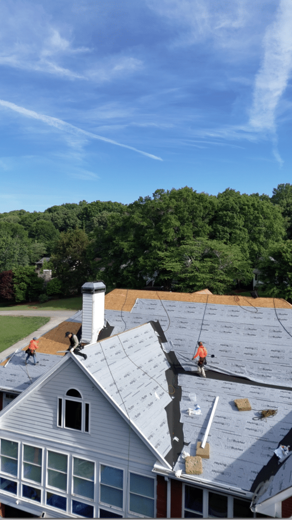 A roof replacement in progress with workers installing underlayment, showing why choose Skyline Contracting for roofing in Omaha by Anchor Roofing.