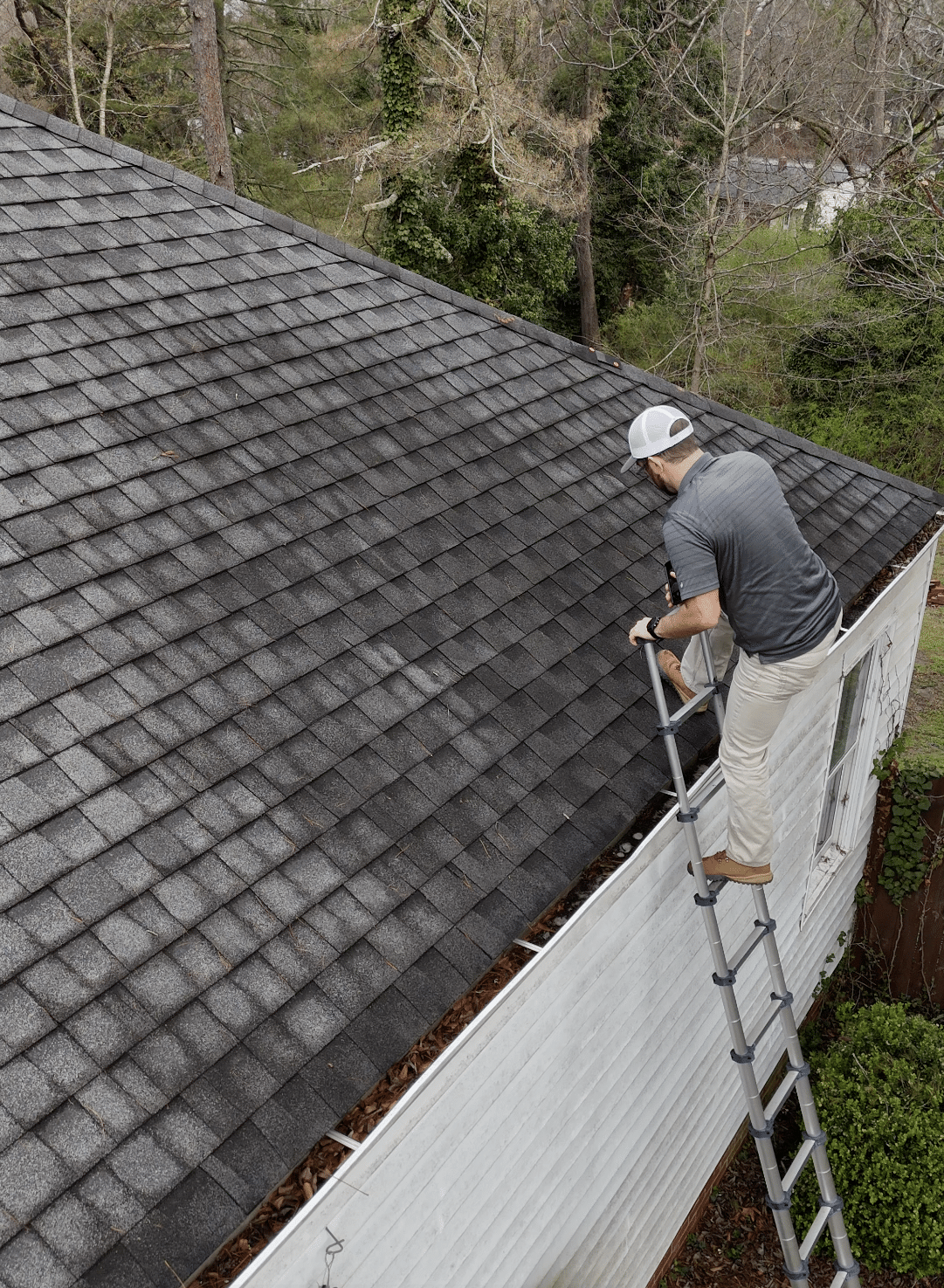 A technician standing on an extension ladder to assess shingle damage for an instant roof estimate roofing service in Gainesville by Skyline Contracting