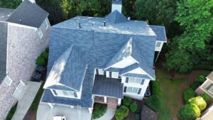 An aerial drone view of a large two-story residential home featuring a complex, newly installed grey asphalt shingle roof, illustrating standard roof insurance check rules roofing service in Gainesville by Skyline Contracting