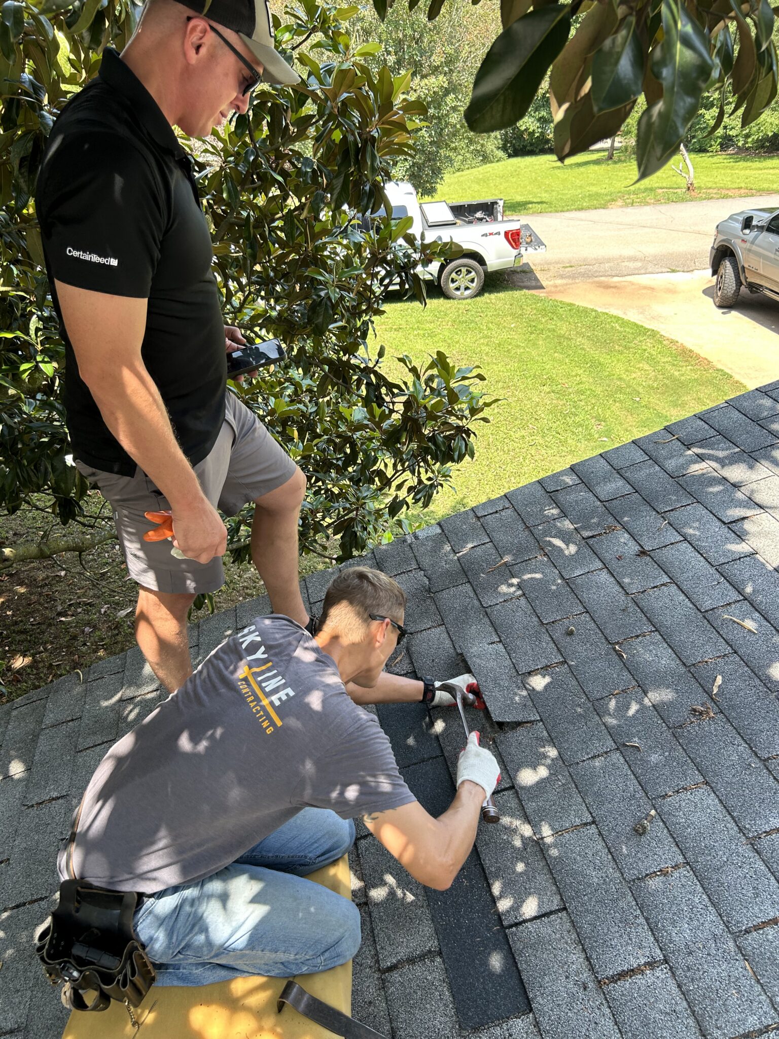 A Skyline Contracting team member using a hammer to lift and repair grey asphalt shingles during a roof insurance check rules roofing service in Gainesville by Skyline Contracting