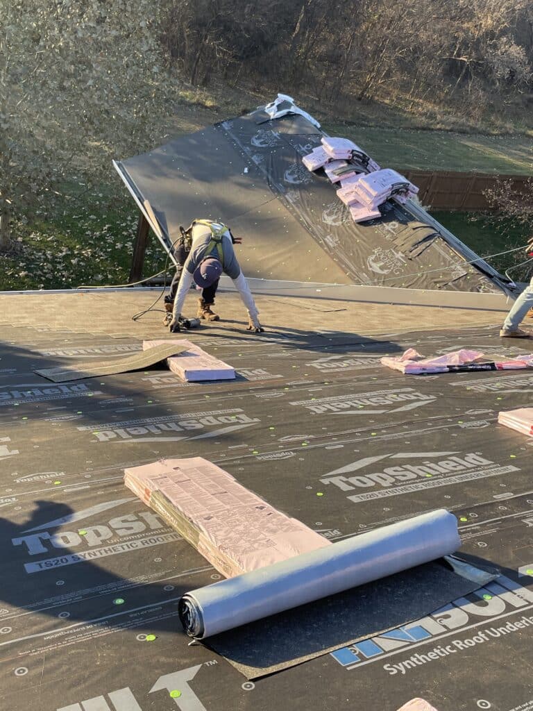Roofer securing synthetic underlayment on a wide roof surface to prepare for seasonal weather based on fall roofing tips residential roof installation in Omaha by Anchor Roofing