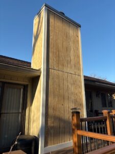 Newly installed vertical wood siding and trim on a residential chimney enclosure during a house siding replacement process siding replacement service in Gainesville by Skyline Contracting