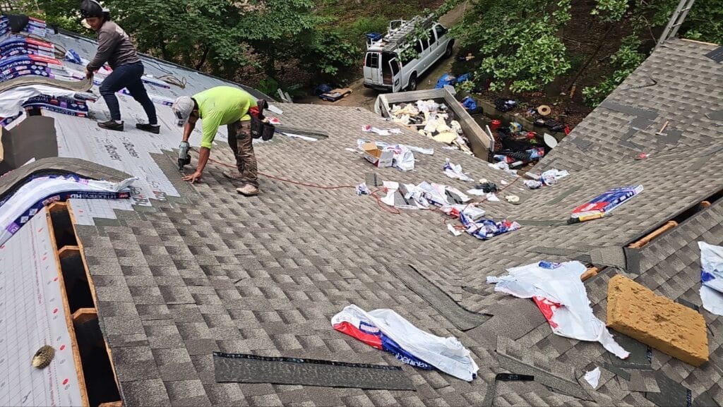 Roofing contractors installing new grey architectural shingles and ridge ventilation during an insurance roof replacement roofing service in Gainesville by Skyline Contracting