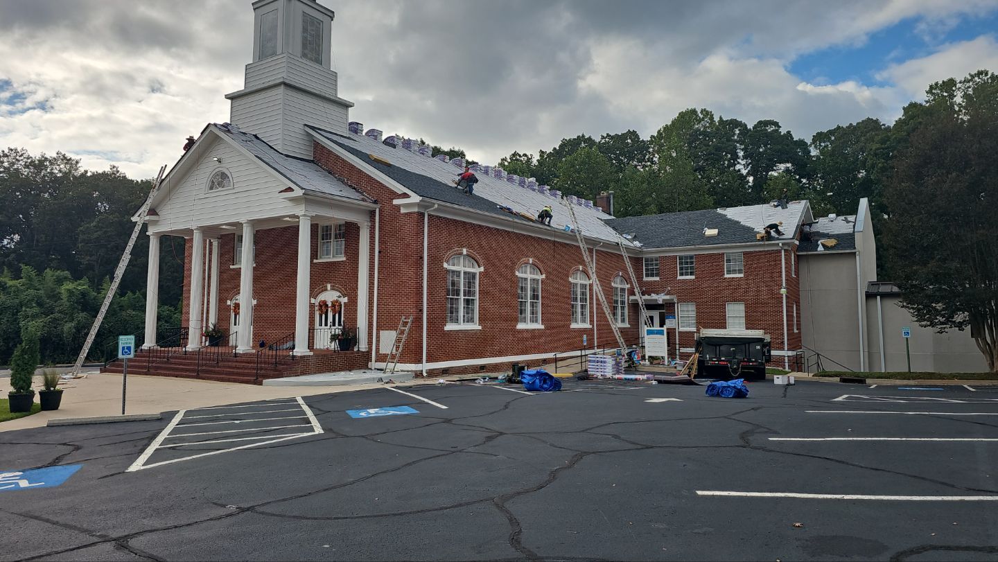Workers repairing brick church roof church roofing contractor service in Gainesville GA by Skyline Contracting