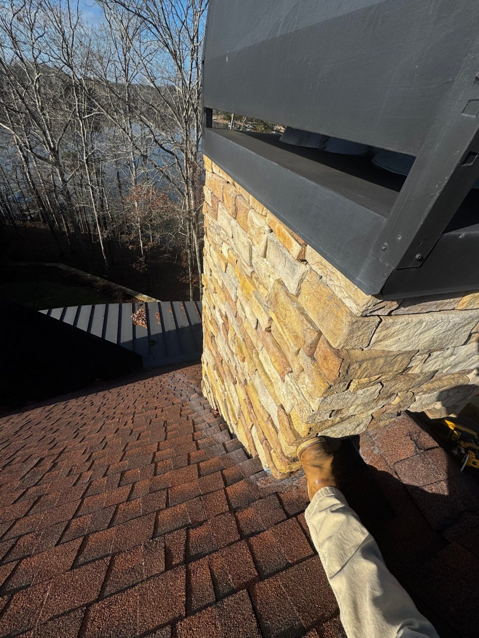 Contractor inspecting stone chimney flashing following a hail damage roof guide in Gainesville, GA by Skyline Contracting